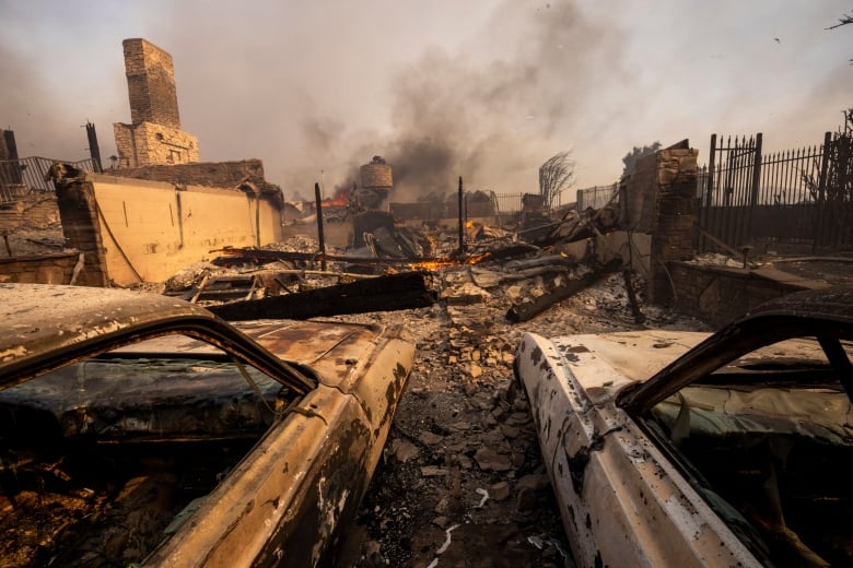 Destruction caused by the Mountain Fire, with smoke billowing in the background